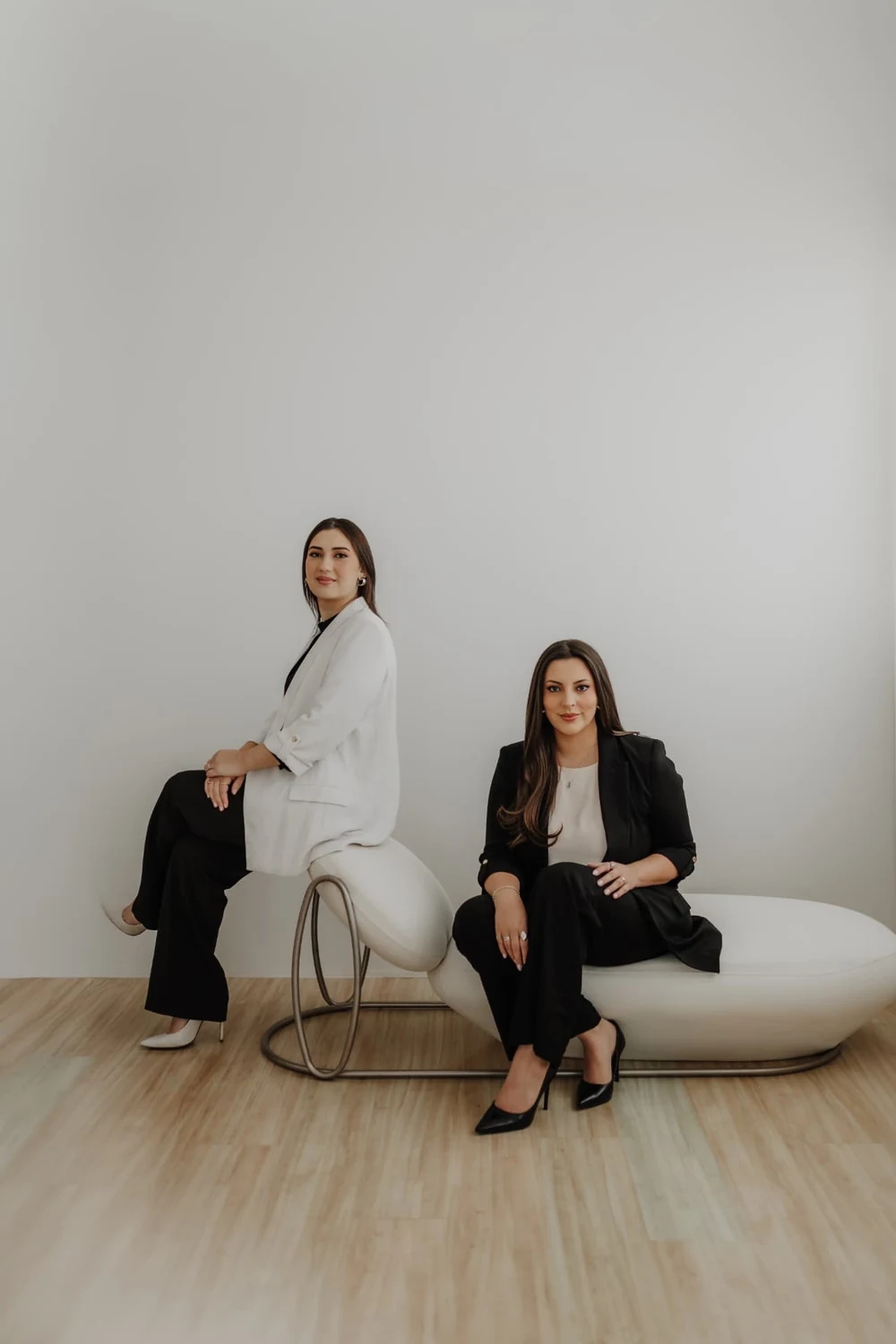 Jéssika Neckel e Gabrieli Albuquerque sentadas em um banco de design, no estúdio do escritório